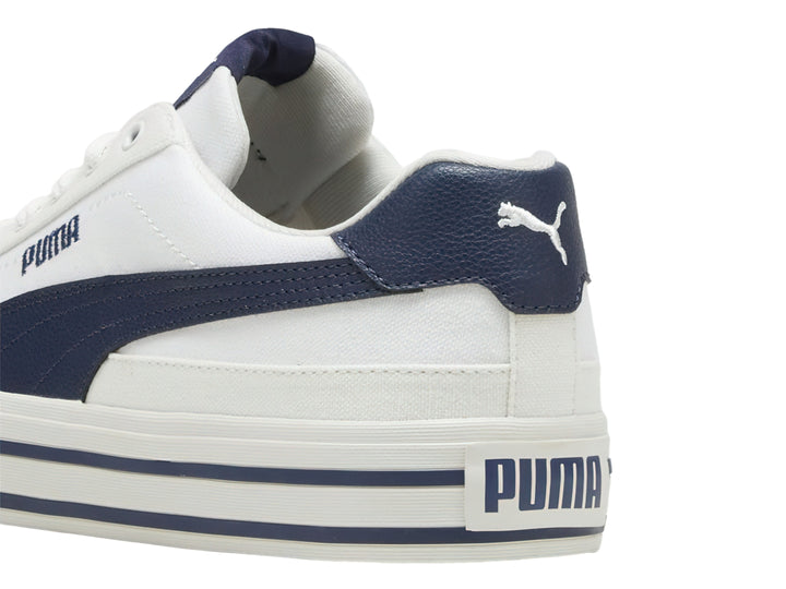 Tenis PUMA Court Classic Vulc en color blanco con detalles en azul marino y suela blanca con rayas laterales azules.