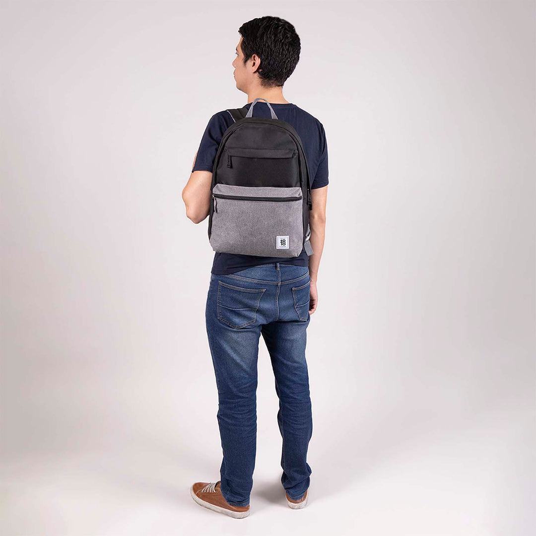 Mochila juvenil marca Chenson en colores negro y gris con bolsillo frontal con cierre.