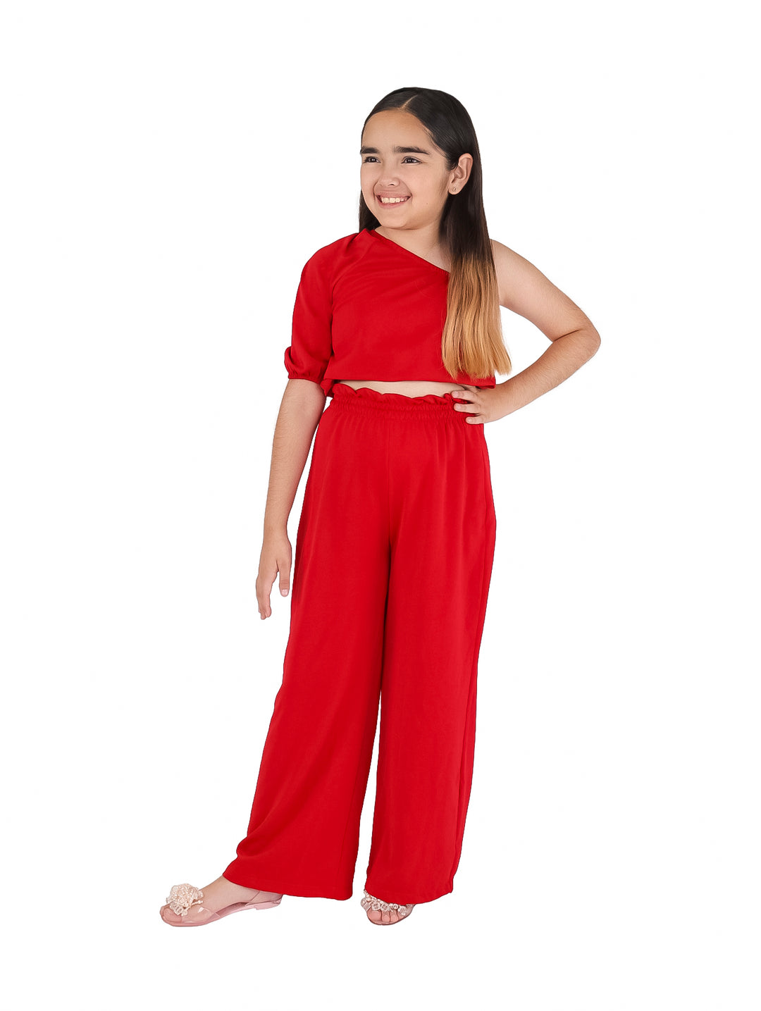 Niña vistiendo un conjunto de dos piezas color rojo con top asimétrico y pantalón ancho.