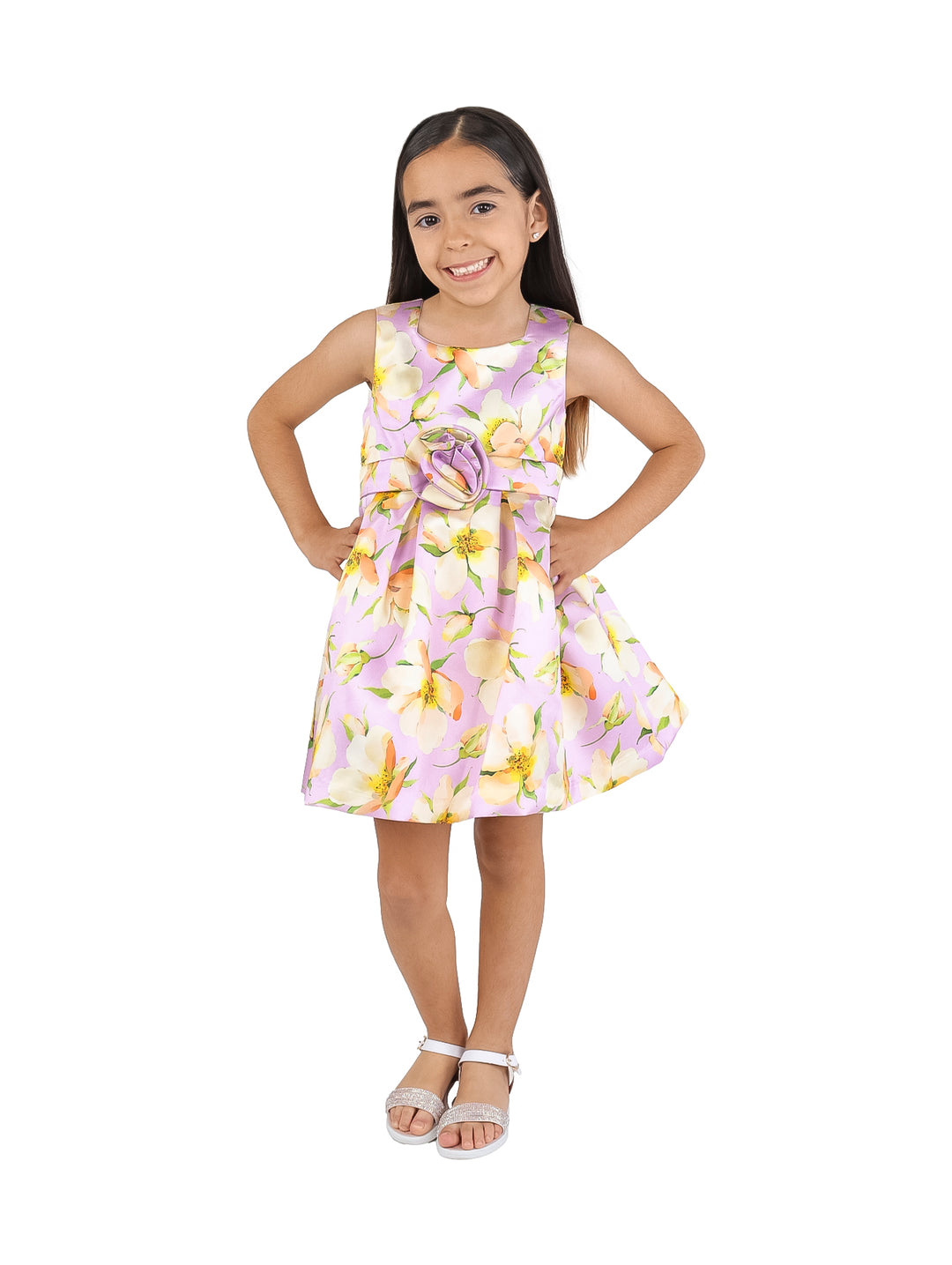 Niña vistiendo un vestido corto color malva con estampado floral amarillo y blanco y detalle de flor en la cintura.