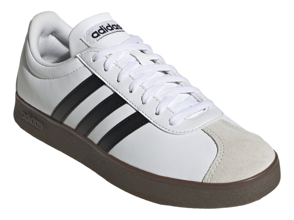 Tenis Adidas blancos con tres rayas negras, punta gris y suela marrón.