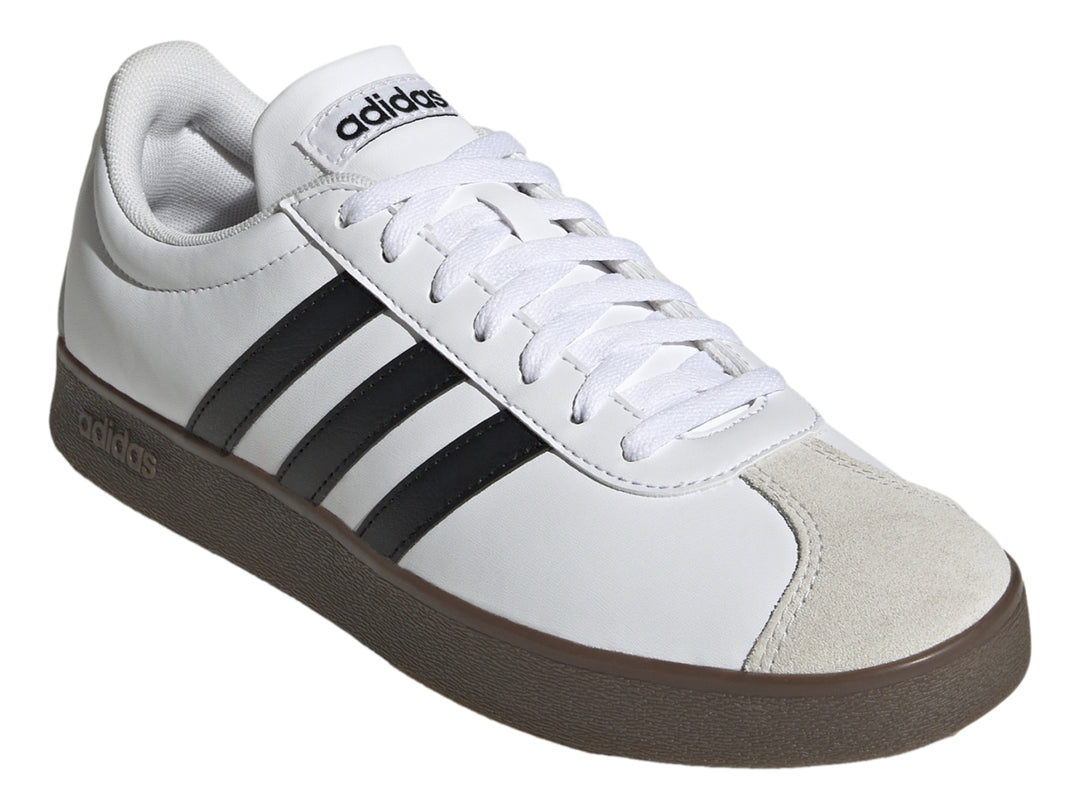 Tenis Adidas blancos con tres rayas negras, punta gris y suela marrón.