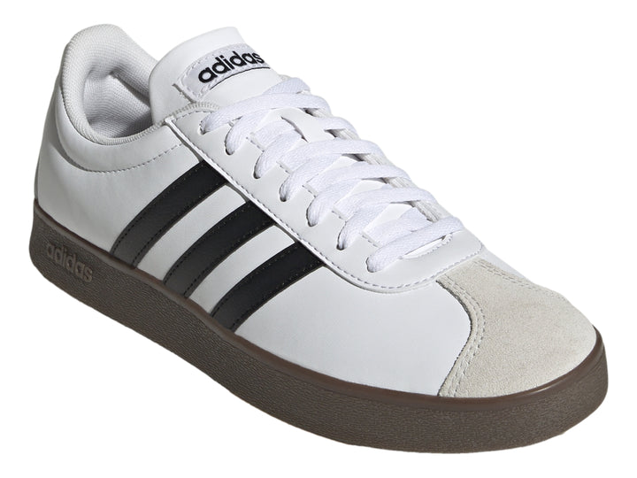 Tenis Adidas blancos con tres rayas negras, punta gris y suela marrón.