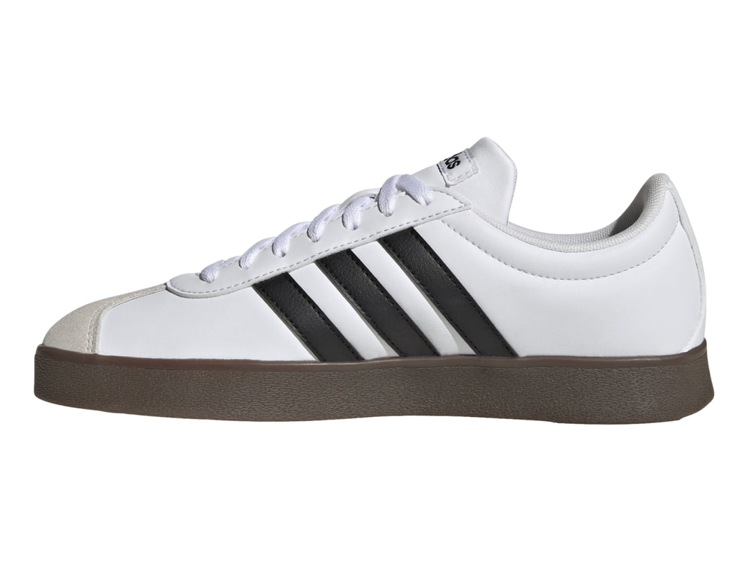 Tenis Adidas blancos con tres rayas negras, punta gris y suela marrón.