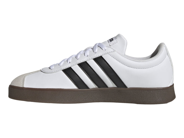 Tenis Adidas blancos con tres rayas negras, punta gris y suela marrón.