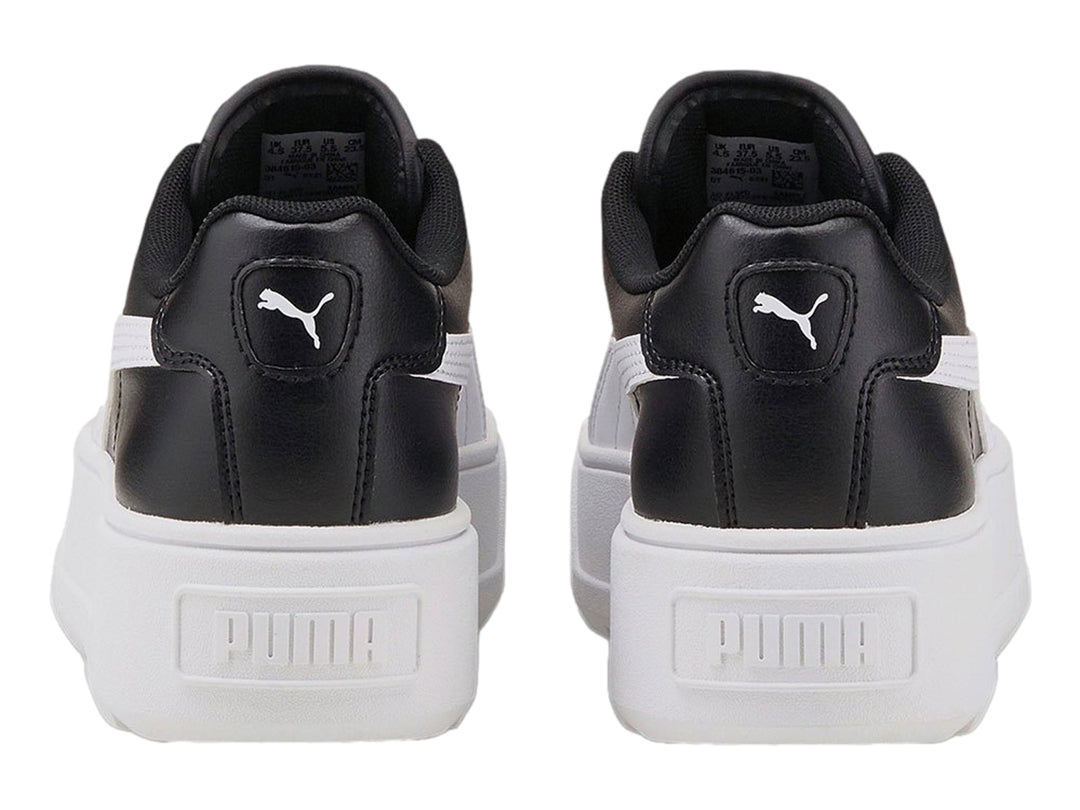 Tenis PUMA color negro con suela de plataforma blanca y franja lateral blanca.