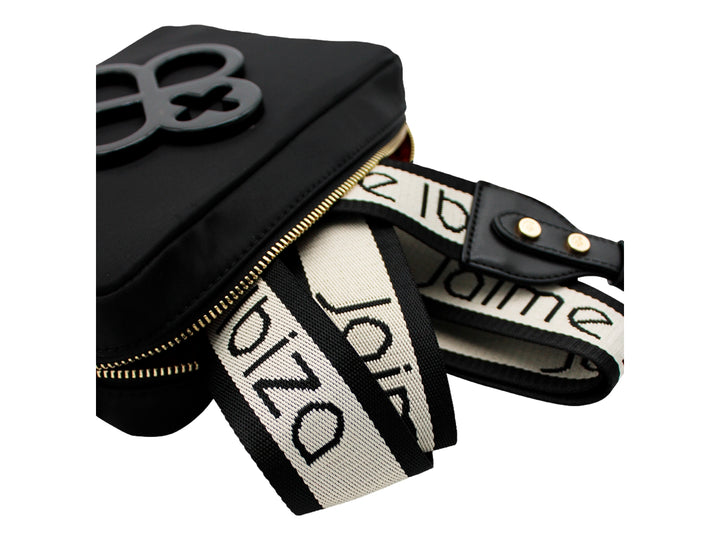 Bolso pequeño color negro con correa y un emblema decorativo frontal.