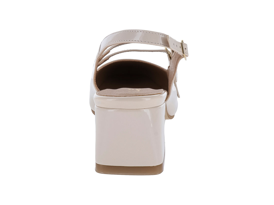Zapato cerrado de charol color beige con tacón bloque y correas con hebillas doradas.