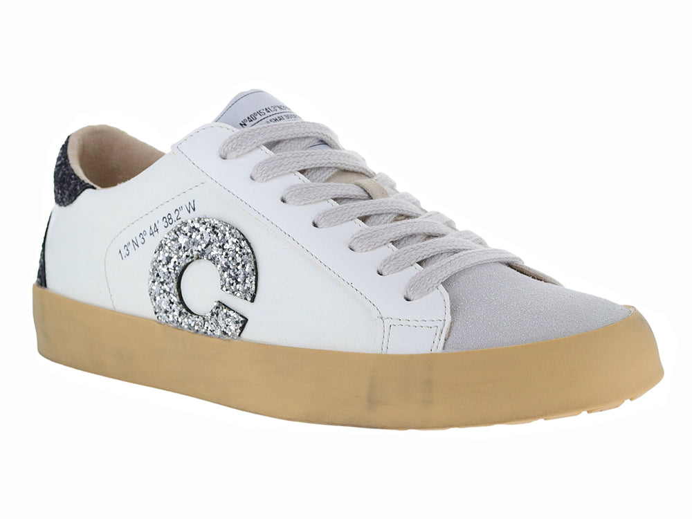 Tenis blancos casuales con detalles brillantes en negro y plata y suela color beige.