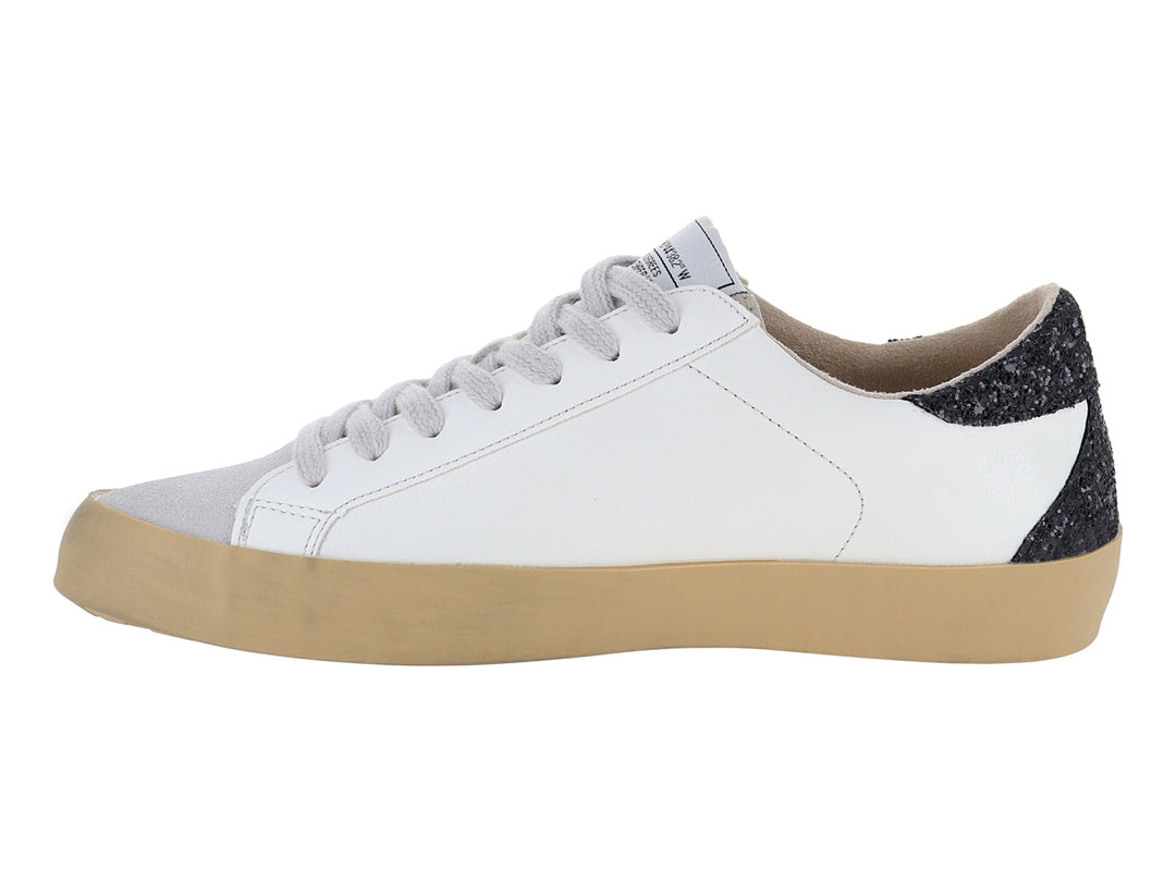 Tenis blancos casuales con detalles brillantes en negro y plata y suela color beige.