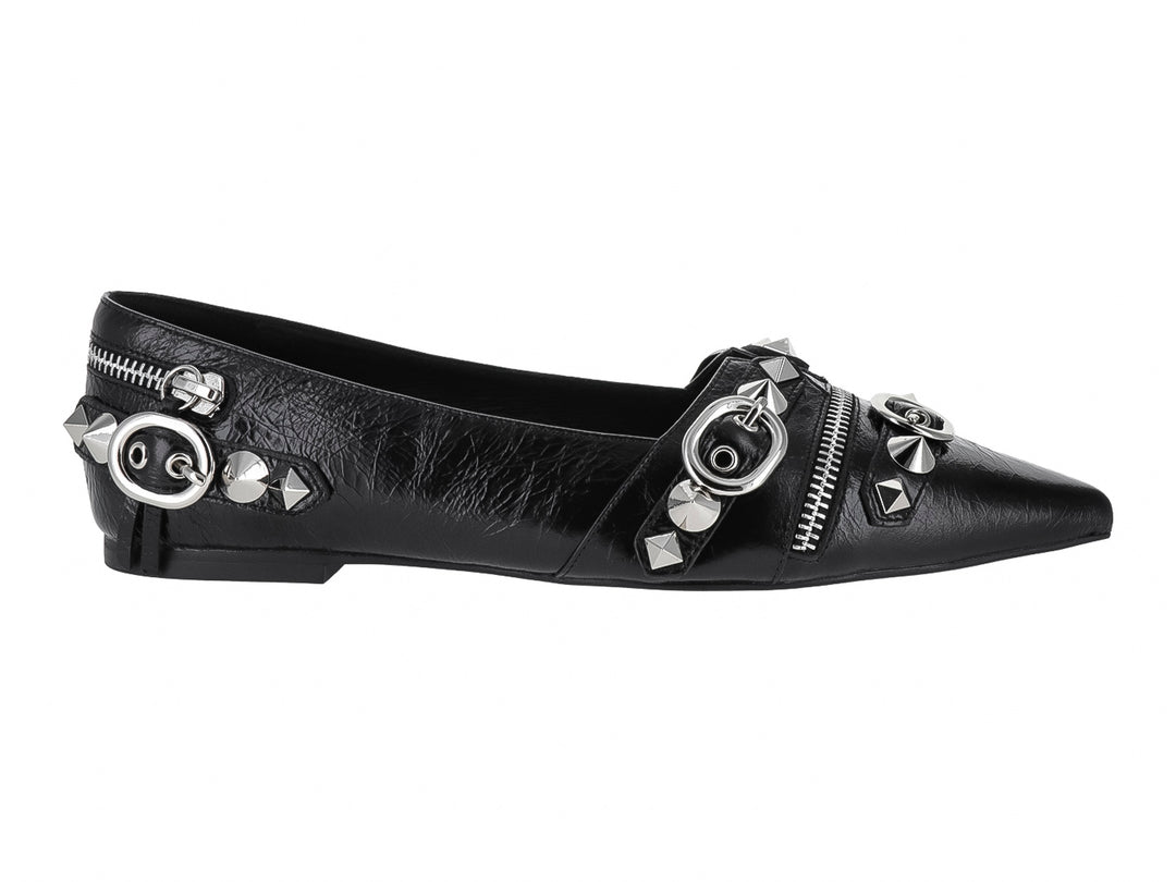 Zapato plano negro de punta afilada con detalles decorativos de cierres, anillos y tachuelas plateadas.