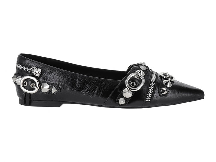 Zapato plano negro de punta afilada con detalles decorativos de cierres, anillos y tachuelas plateadas.