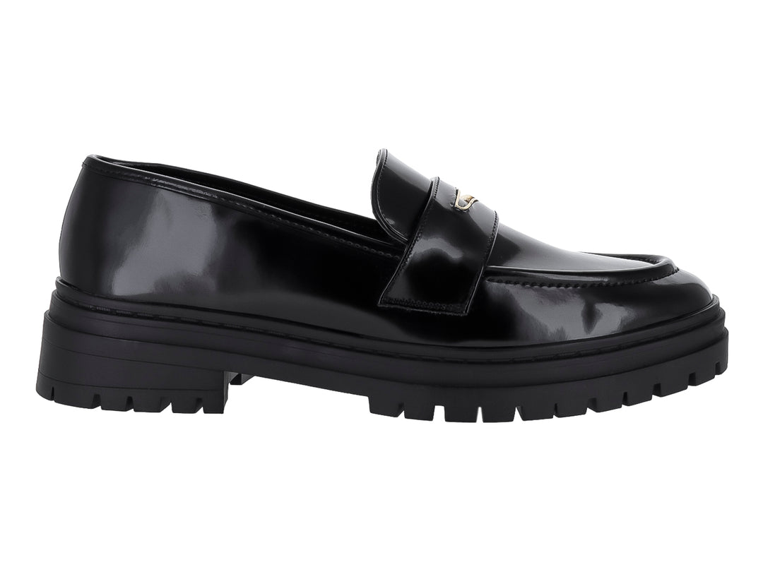 Zapato tipo mocasín negro de alto brillo con suela track gruesa y detalle metálico.