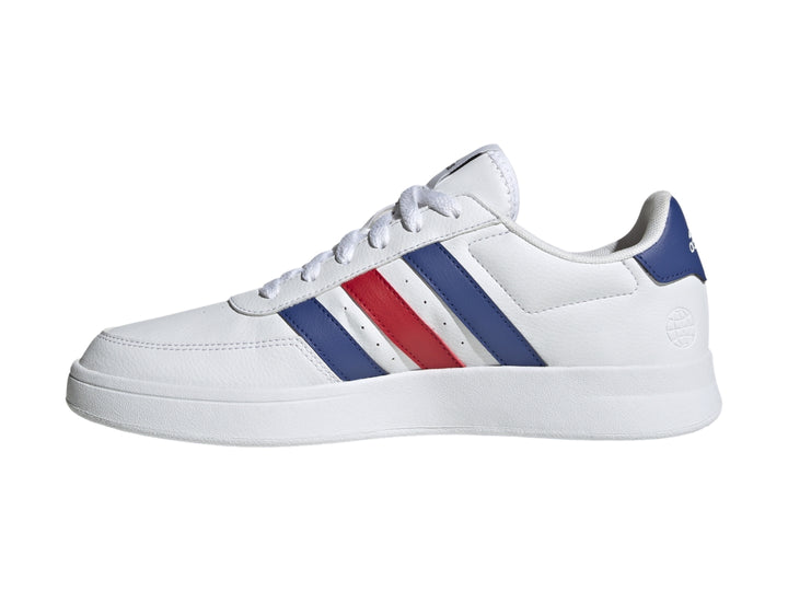 Tenis Adidas blancos con tres franjas laterales en azul y rojo y suela blanca.