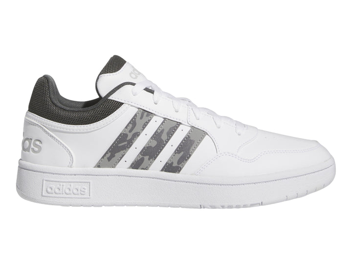 Tenis Adidas blancos con detalles en gris y rayas laterales con patrón de camuflaje.