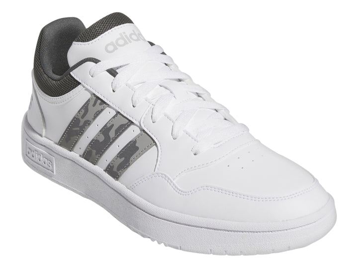 Tenis Adidas blancos con detalles en gris y rayas laterales con patrón de camuflaje.