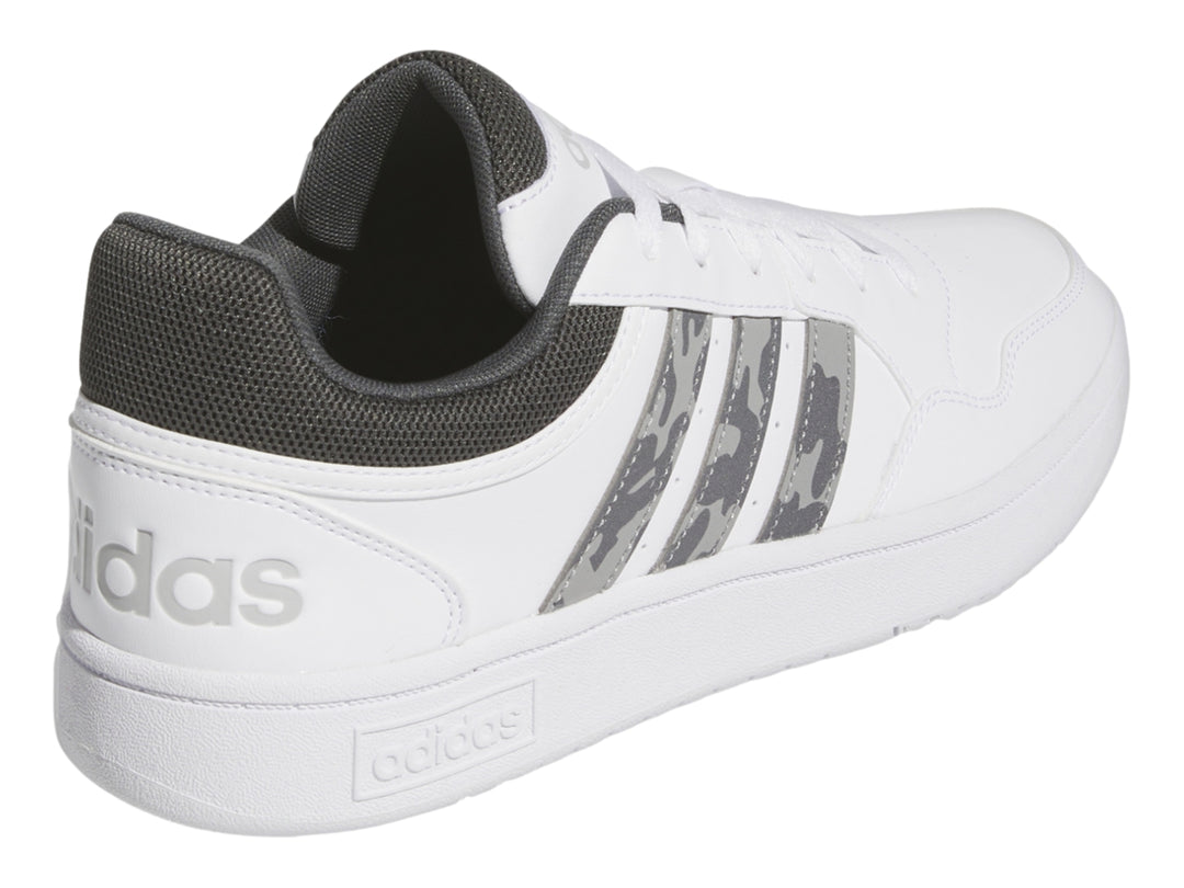 Tenis Adidas blancos con detalles en gris y rayas laterales con patrón de camuflaje.