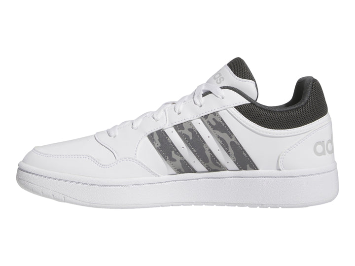 Tenis Adidas blancos con detalles en gris y rayas laterales con patrón de camuflaje.