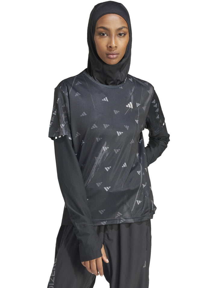 Mujer vistiendo camiseta deportiva Adidas negra de manga larga con estampado sutil y hiyab negro.