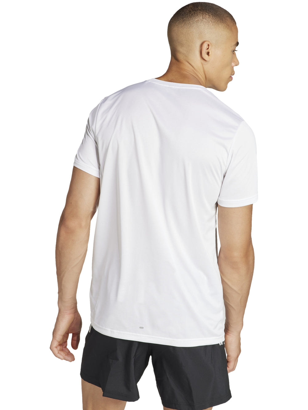 Hombre usando camiseta deportiva blanca Adidas RUN IT TEE con logo negro en el pecho.