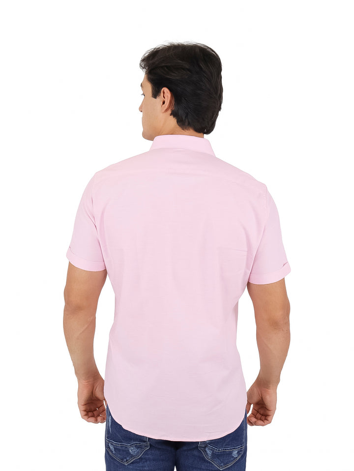 Hombre vistiendo una camisa de manga corta color rosa con cuello y un bolsillo frontal.