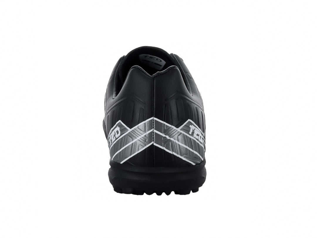 Zapato de fútbol Leon Trucco FT90 color negro con detalles gráficos en blanco y suela para pasto sintético.