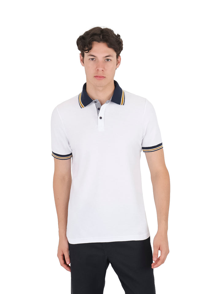 Hombre vistiendo playera polo blanca con detalles en azul marino y dorado en el cuello y mangas.