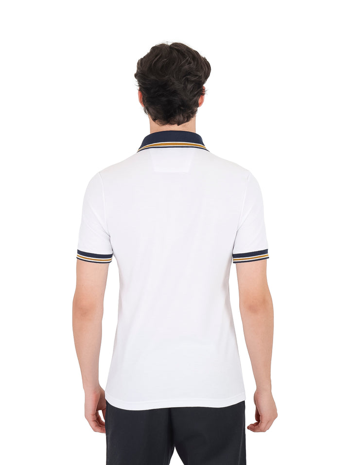 Hombre vistiendo playera polo blanca con detalles en azul marino y dorado en el cuello y mangas.