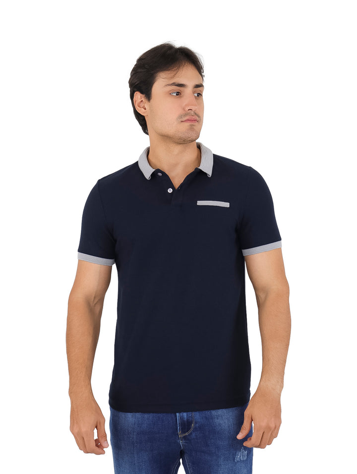 Hombre vistiendo playera polo color azul marino con detalles en gris en el cuello, mangas y pecho.