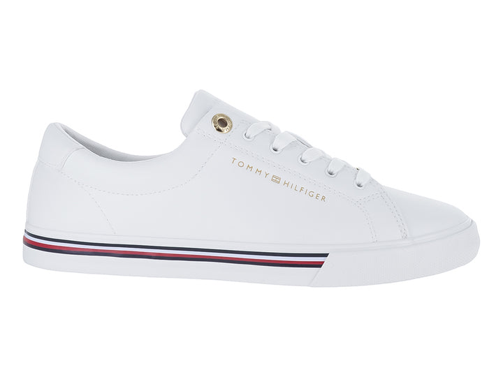 Tenis blancos Tommy Hilfiger estilo court con franjas azul y roja en la suela y logotipo dorado.