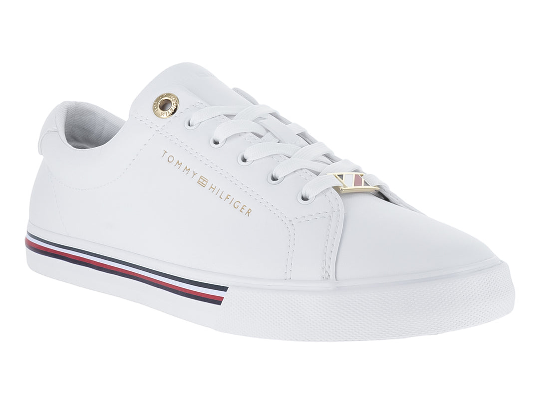 Tenis blancos Tommy Hilfiger estilo court con franjas azul y roja en la suela y logotipo dorado.