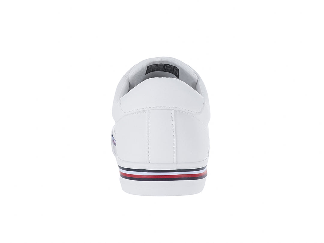 Tenis blancos Tommy Hilfiger estilo court con franjas azul y roja en la suela y logotipo dorado.