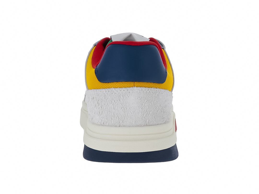 Tenis Tommy Hilfiger color ivory con detalles en azul, rojo y amarillo y suela blanca robusta.
