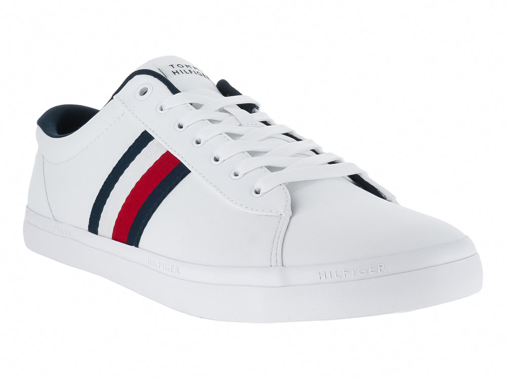 Tenis blancos Tommy Hilfiger con franjas laterales en azul marino y rojo y suela blanca.