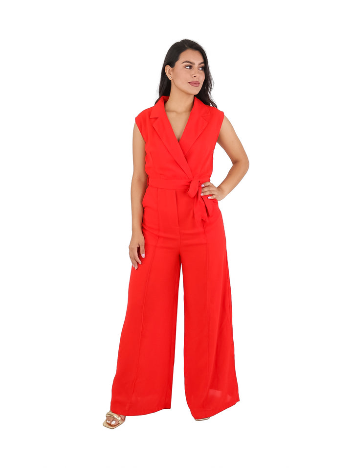 Mujer vistiendo un enterizo color naranja con pantalones palazzo y lazo en la cintura.