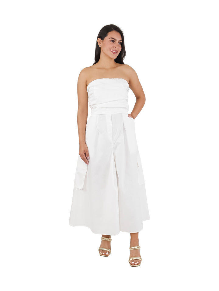 Mujer vistiendo un vestido strapless blanco de corte ancho con bolsillos laterales.