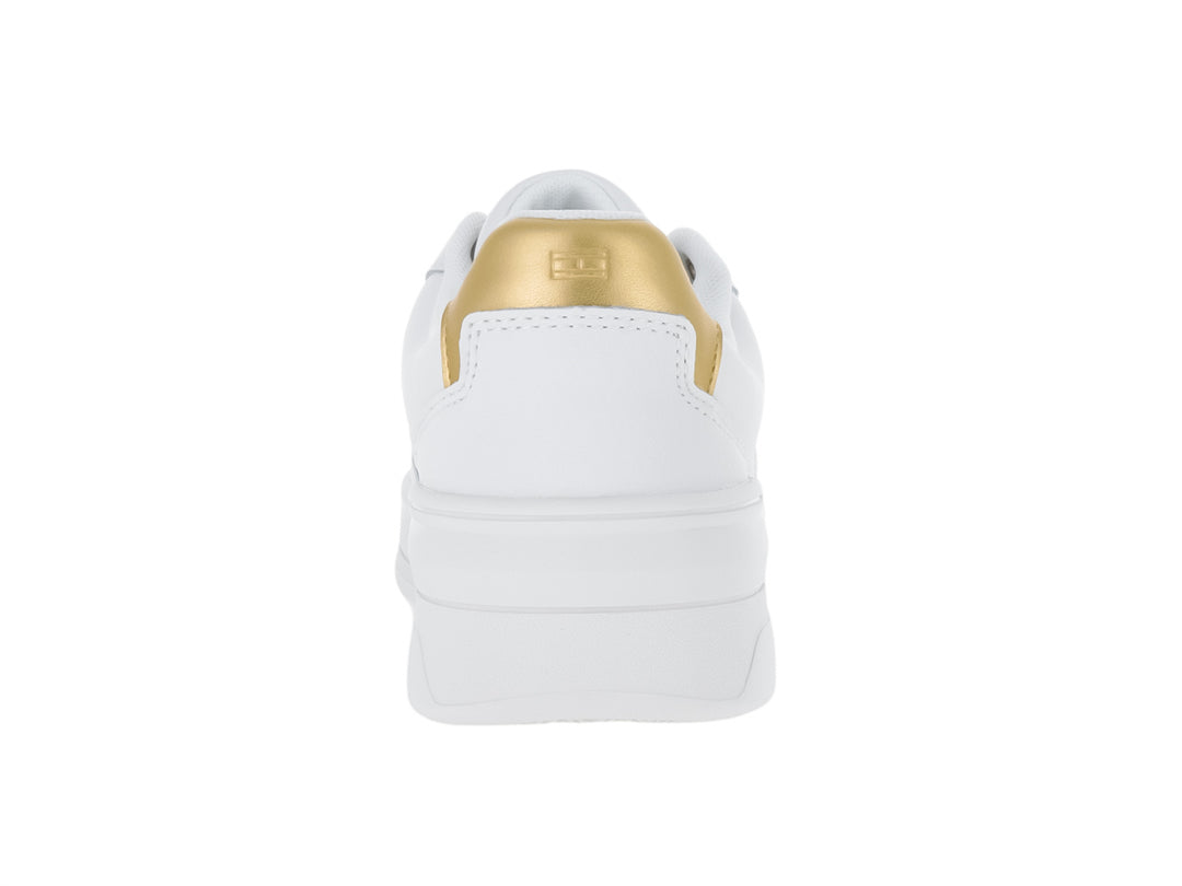 Tenis Tommy Hilfiger color blanco con detalle dorado en el talón y suela ancha blanca.
