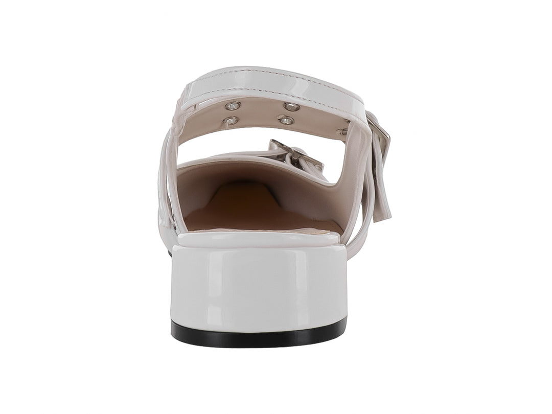 Zapato color latte de charol brillante con punta afilada, tacón bajo y dos hebillas plateadas decorativas.