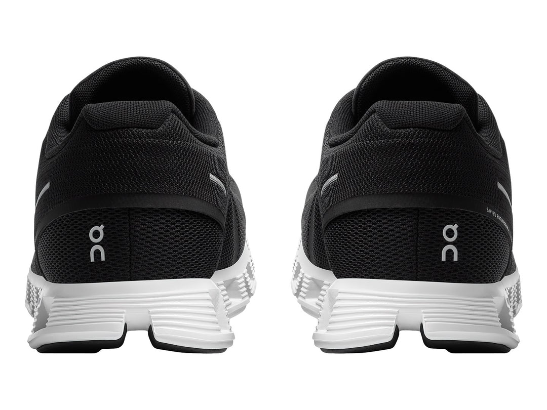 Tenis deportivos On Cloud 5 en color negro con suela blanca segmentada y detalles minimalistas.