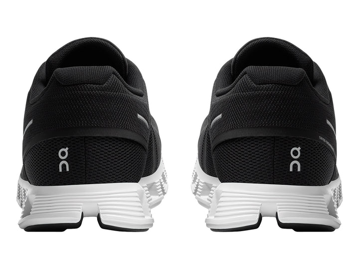 Tenis deportivos On Cloud 5 en color negro con suela blanca segmentada y detalles minimalistas.