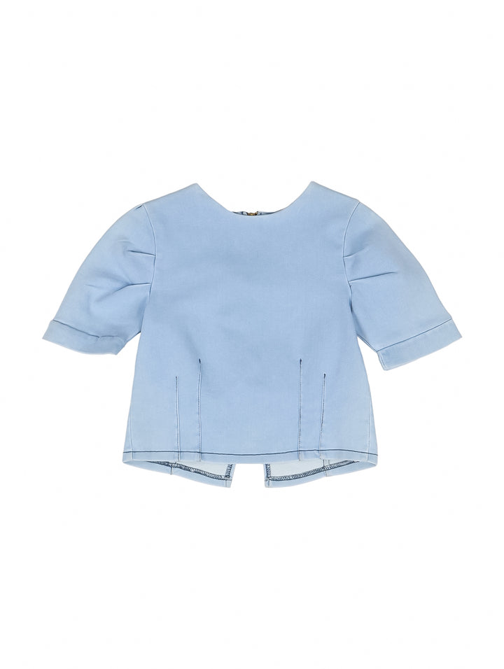 Niña vistiendo una blusa de manga corta color azul claro light denim y pantalones de mezclilla.