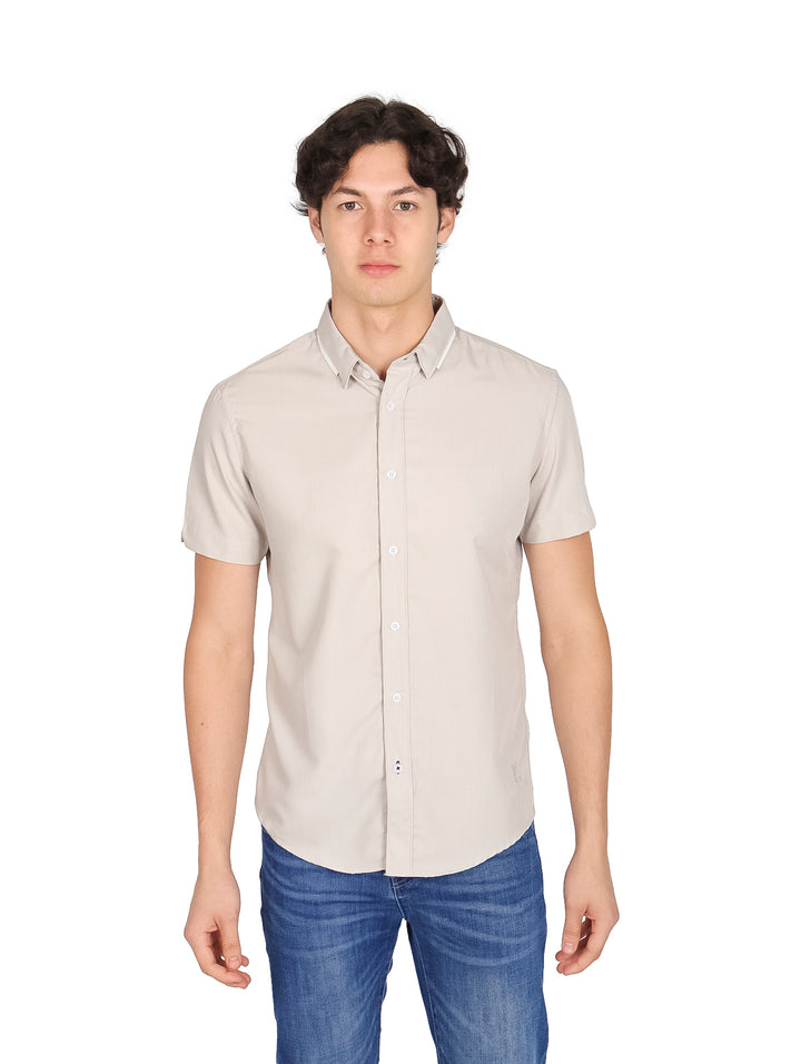 Hombre vistiendo una camisa casual de manga corta color gris claro y jeans azules.