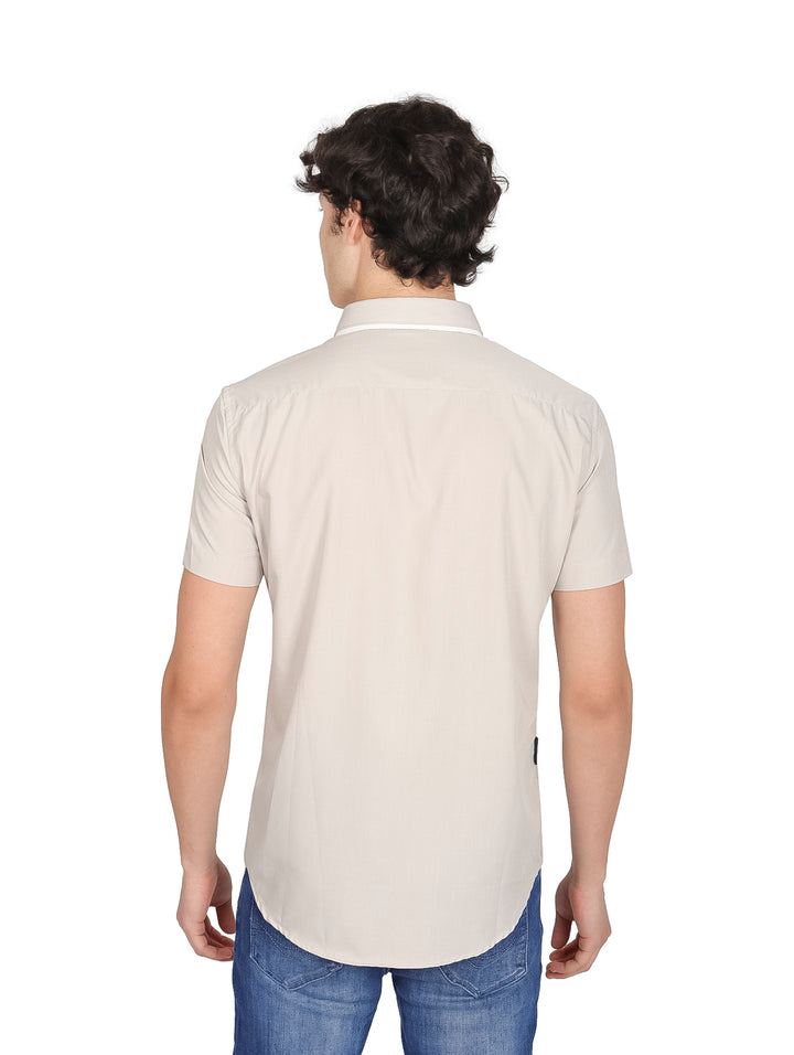 Hombre vistiendo una camisa casual de manga corta color gris claro y jeans azules.