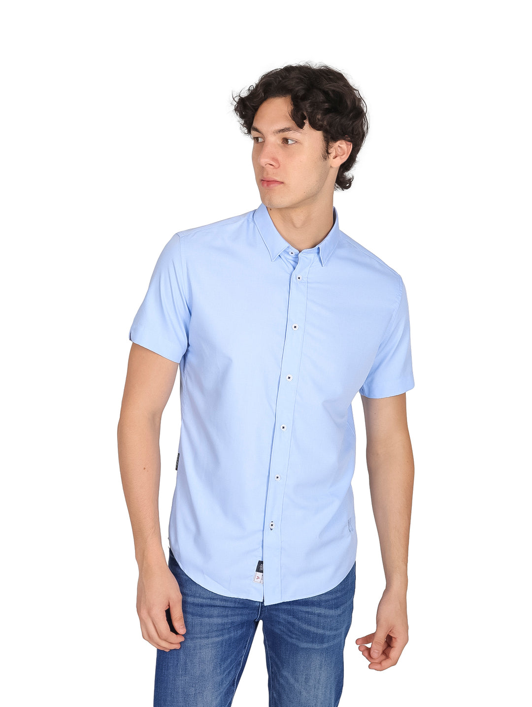 Hombre vistiendo una camisa de manga corta color azul claro y pantalones de mezclilla.