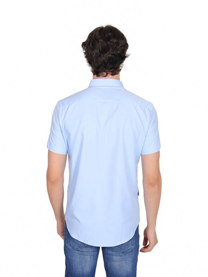 Hombre vistiendo una camisa de manga corta color azul claro y pantalones de mezclilla.