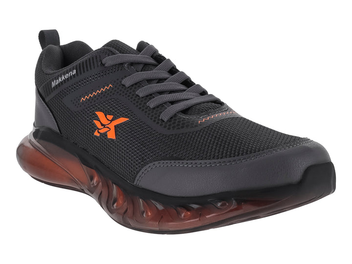 Zapato deportivo para niño marca Makkena en color gris oscuro con detalles y suela en tono naranja.