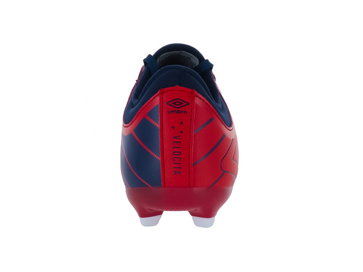 Botín de fútbol Umbro color rojo con detalles en azul y suela blanca con estoperoles.