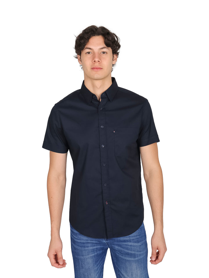 Hombre vistiendo una camisa de manga corta color azul marino lisa con cuello y botones.