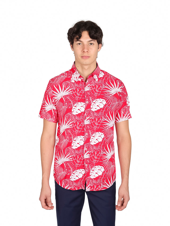 Hombre vistiendo camisa roja de manga corta con estampado de hojas blancas y pantalones azul marino.