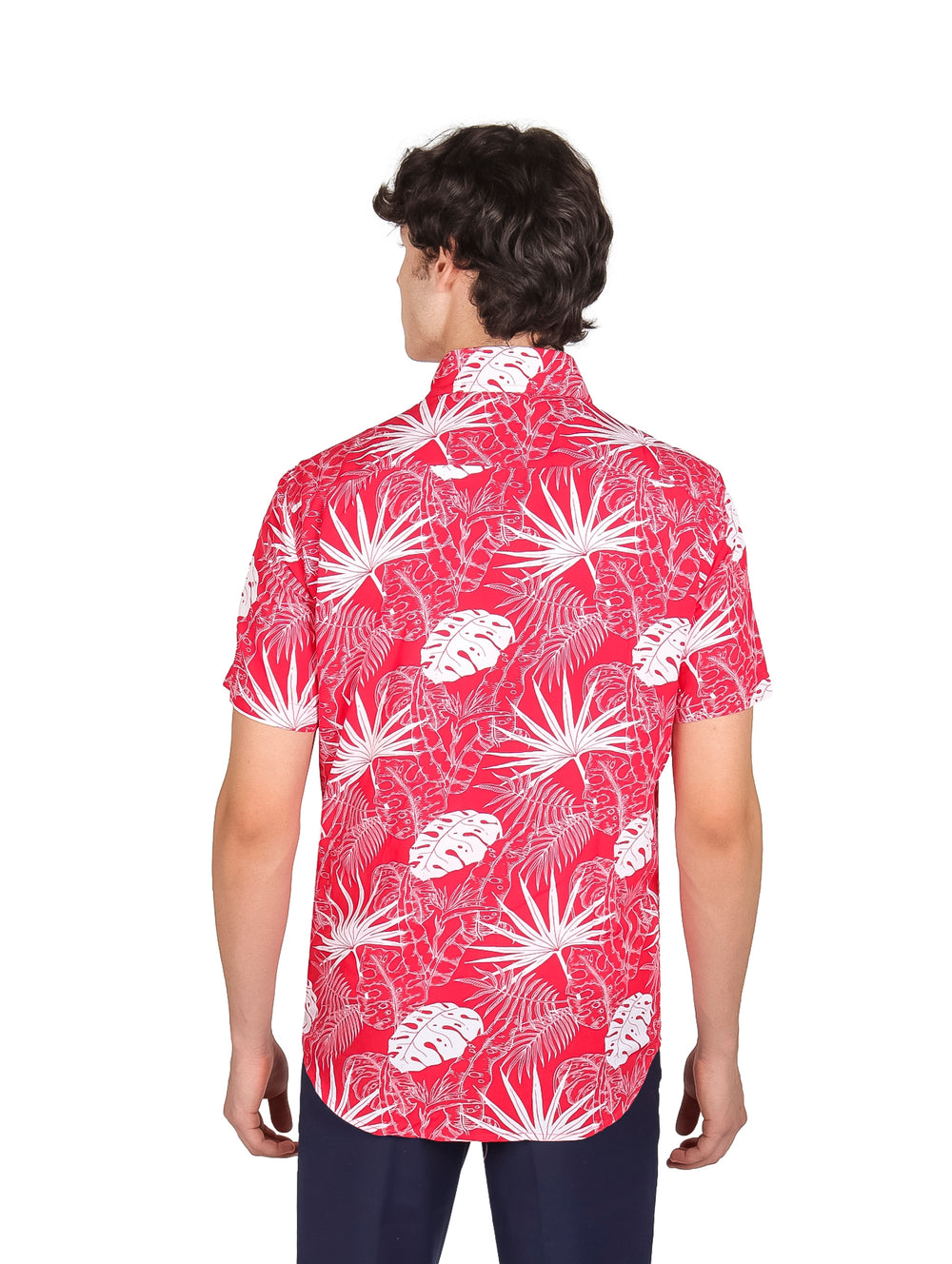 Hombre vistiendo camisa roja de manga corta con estampado de hojas blancas y pantalones azul marino.